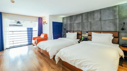 een hotelkamer met 2 bedden en een oranje stoel bij VIZ Culture & Arts Apartment in Nanning