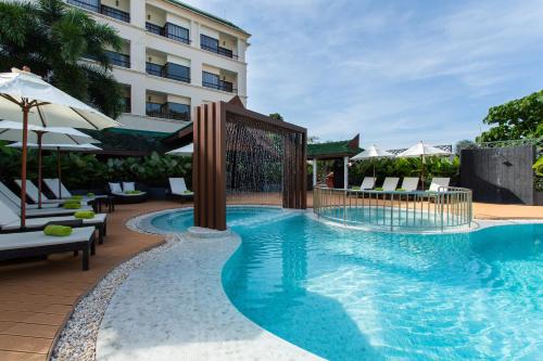 a pool at a hotel with chairs and umbrellas at Krabi Heritage Hotel in Ao Nang Beach