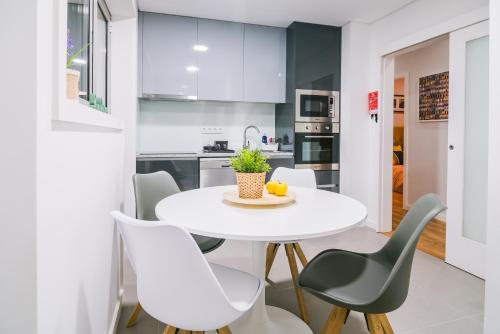 cocina blanca con mesa blanca y sillas en Lechartier Oporto apartments 3, en Oporto