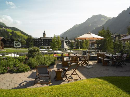 a patio with a table and chairs and an umbrella at Apart-Hotel Filomena in Lech am Arlberg