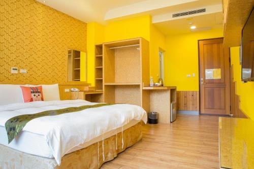 a bedroom with a large bed and yellow walls at Yuan Su B&B in Yuchi