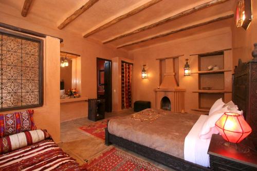 een slaapkamer met een bed en een open haard en een bank bij Jnane Leila in Marrakesh