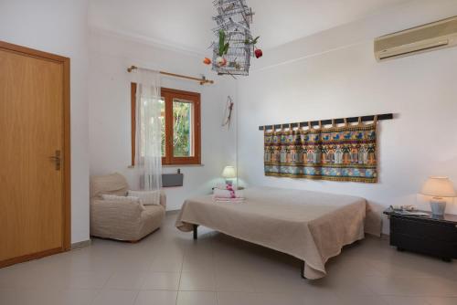 サン・ヴィート・ロ・カーポにあるVilletta di babiのベッドルーム1室(ベッド1台、椅子、窓付)