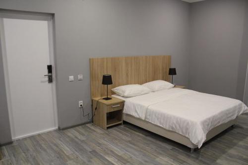 um quarto com uma cama e uma mesa de cabeceira com um candeeiro em Hotel Inju Hills em Astana