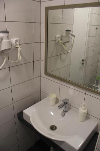 a white bathroom with a sink and a mirror at Hotel Inju Hills in Astana