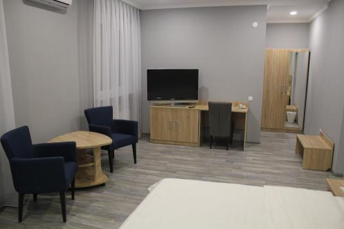 阿斯塔纳Hotel Inju Hills的一间配有电视、椅子和桌子的等候室