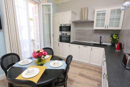 une cuisine avec une table et des chaises et une cuisine avec des armoires blanches dans l'établissement Le Charme-35, à Nice