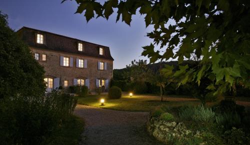 a large brick building with lights in the yard at Les Glycines - Hôtel & Spa - Teritoria in Les Eyzies-de-Tayac