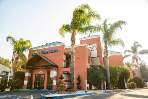 a hotel with palm trees in front of a building at Days Inn by Wyndham Concord in Concord