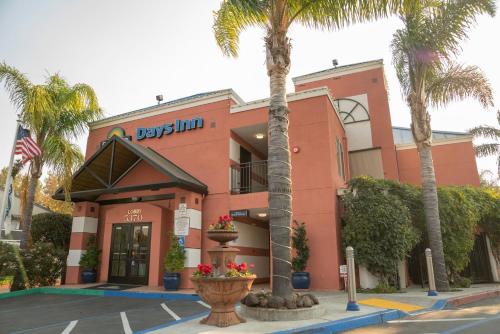 a pink building with palm trees in front of it at Days Inn by Wyndham Concord in Concord