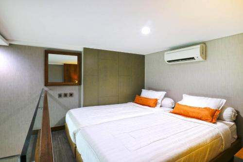 a bedroom with a large white bed with orange pillows at The Baile in Jakarta