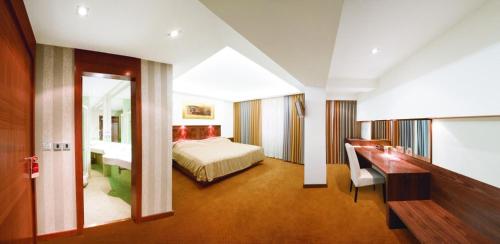 Habitación de hotel con cama, escritorio y espejo. en Hotel Exclusive, en Sarajevo