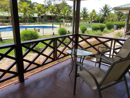 a balcony with chairs and a table and a pool at Overbridge River Resort in Paramaribo