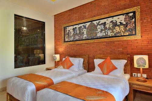 two beds in a room with a brick wall at Green Field Resort Ubud in Ubud