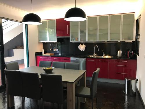 a kitchen with red cabinets and a table with chairs at Casa Gama in Ribeira Brava