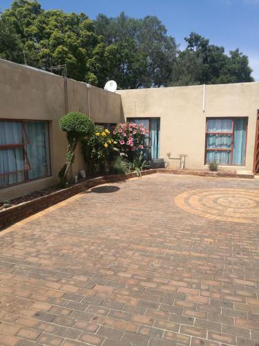 a brick driveway in front of a building with flowers at Naisar Sparkling Apartment in Germiston