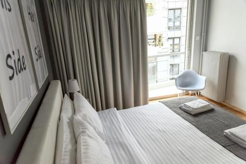 um quarto com uma cama e uma janela com uma cadeira em Penelope's Luxury Apartment em Atenas