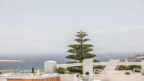 a palm tree on a balcony with a table and chairs at Iliada Villas in Agios Prokopios