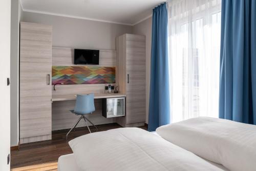 sypialnia z łóżkiem, telewizorem i oknem w obiekcie Westend Hotel (non-smoking) w Monachium