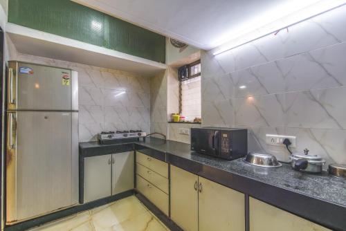 a kitchen with a refrigerator and a microwave at Nest Dormitory in Mumbai