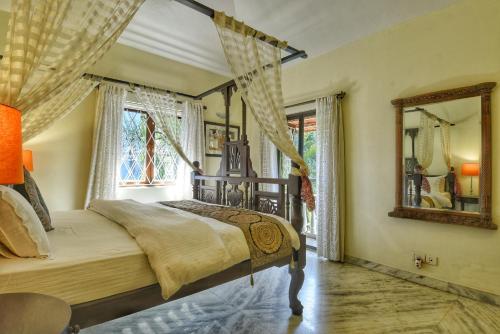 een slaapkamer met een hemelbed en een spiegel bij Villa Samaara9 Candolim Beach in Candolim