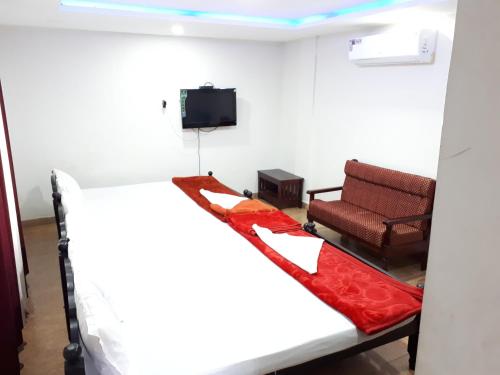 a room with a bed and a chair at Deluxe Residency in Kalpetta