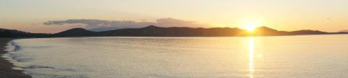 a sunset over a body of water with mountains in the background at Villa in Marathonos in Schinias