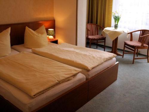 Habitación de hotel con cama, mesa y sillas en Hotel-Pension Ursula en Bad Sachsa