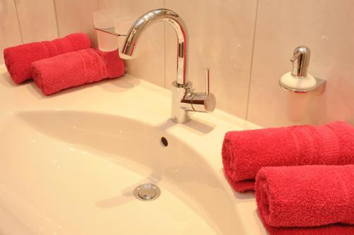 La salle de bains est pourvue d'un lavabo et de serviettes rouges. dans l'établissement Appartment Valnova / Barga, à Partenen