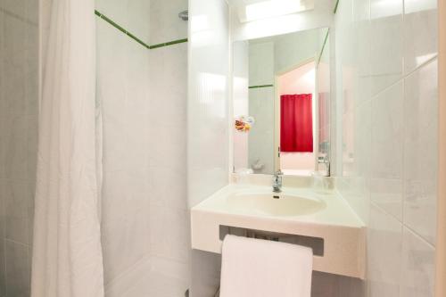 a white bathroom with a sink and a mirror at Premiere Classe Bordeaux Nord - Lac in Bordeaux