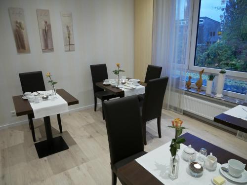 ein Esszimmer mit Tischen, Stühlen und einem Fenster in der Unterkunft Haus Nethegau in Bad Driburg