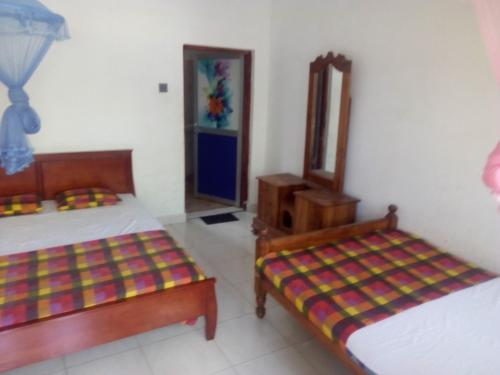 Habitación con 2 camas y espejo. en Dinesh Guest House, en Kataragama