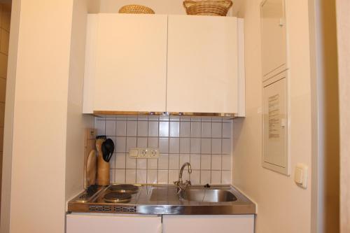 a kitchen with white cabinets and a sink at ZV-Scholtz Burghausen, Mozartstr.15 AP-52 in Burghausen