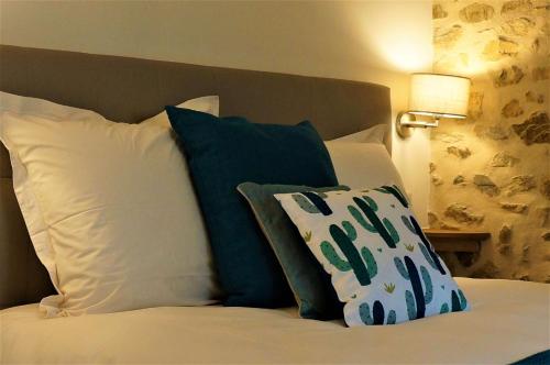 Una cama con almohadas blancas y azules. en B&B Les Tranchées en La Croisille-sur-Briance