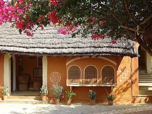 una casa con techo de paja con plantas y flores en Apani Dhani Eco-Lodge, en Nawalgarh