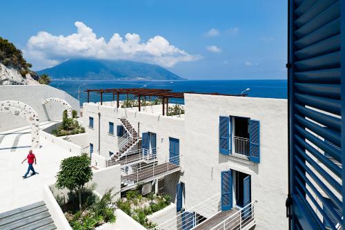 a person walking past a building with the ocean in the background at NerOssidiana in Acquacalda