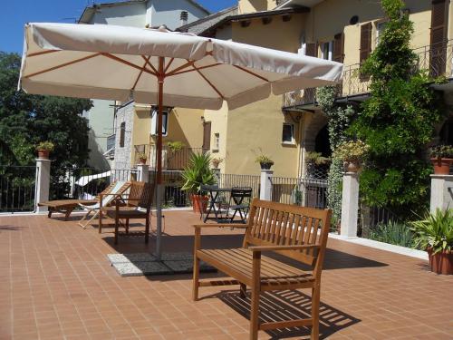 a patio with chairs and an umbrella and tables at Antico Borgo Piceno in Ascoli Piceno