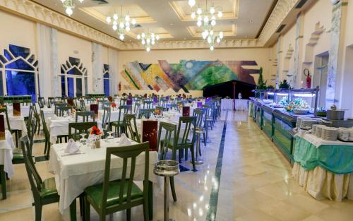 a banquet hall with white tables and green chairs at El Mouradi Douz in Douz