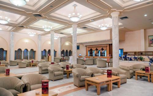 a large lobby with chairs and tables and chandeliers at El Mouradi Douz in Douz