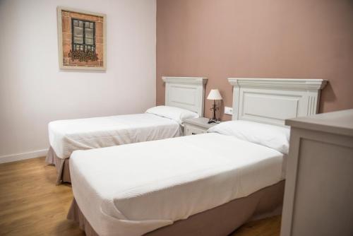 カセレスにあるApartamento Plaza Mayor Cáceresのベッド2台が備わる部屋、壁に絵が飾られた部屋