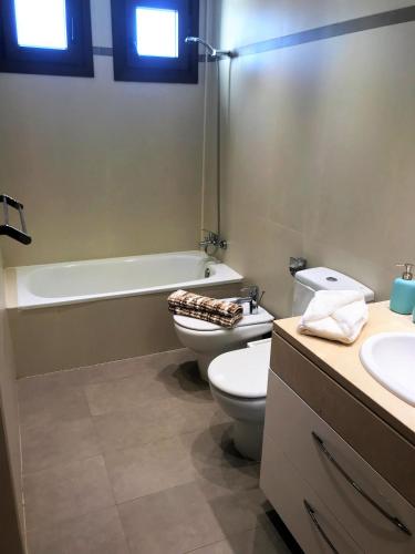 a bathroom with a toilet and a tub and a sink at Noray Swan Duplex right at the Pool in Puerto Calero
