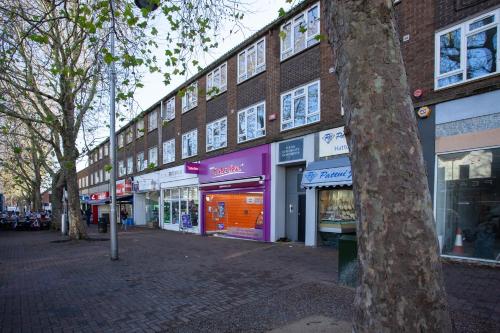 a building with shops on the side of a street at Treetops Apartment in Milton Keynes