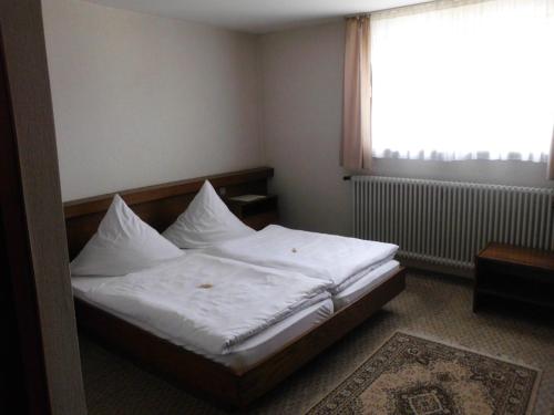 a bedroom with a bed with white sheets and a window at Finken, Gästezimmer an der Rench in Oppenau