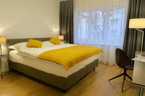 a bedroom with a bed with yellow sheets and a window at Zurich Furnished Homes in Zürich