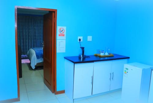 a blue room with a table and a refrigerator at Angel Guest House in Johannesburg
