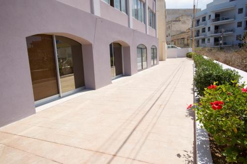 a sidewalk outside of a building with red flowers at Sands in St Julian's
