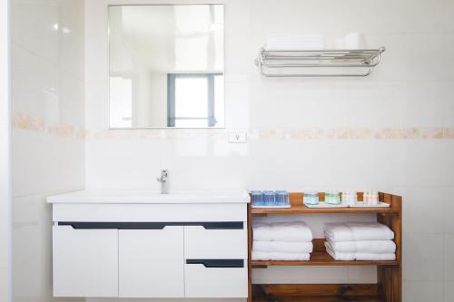 een badkamer met een wastafel, een spiegel en handdoeken bij 5+1 Homestay in Magong