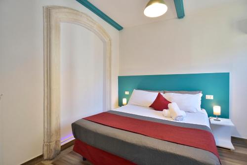 a bedroom with a large bed with a blue headboard at Modica Old Town Rooms in Modica