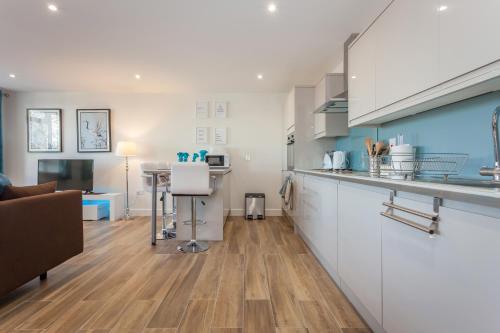 a kitchen with white cabinets and a living room at Treetops Apartment in Milton Keynes
