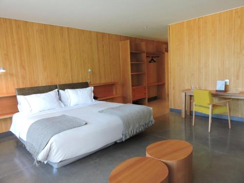 a bedroom with a bed and a table and a desk at Las Majadas Hotel & Centro de Reuniones in Pirque